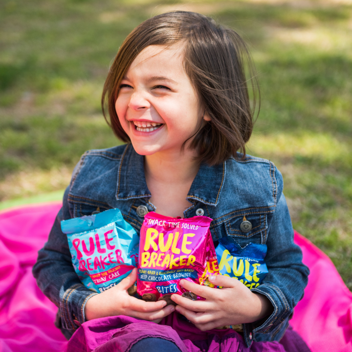 Little girl hold 3 Rule Breaker Bites - Chocolate Chip, Chocolate Brownie and Birthday Cake