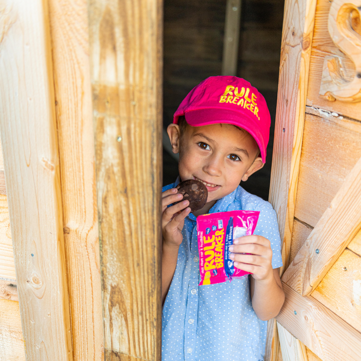 Little boy wearing a pink hat with yellow rule breaker logo