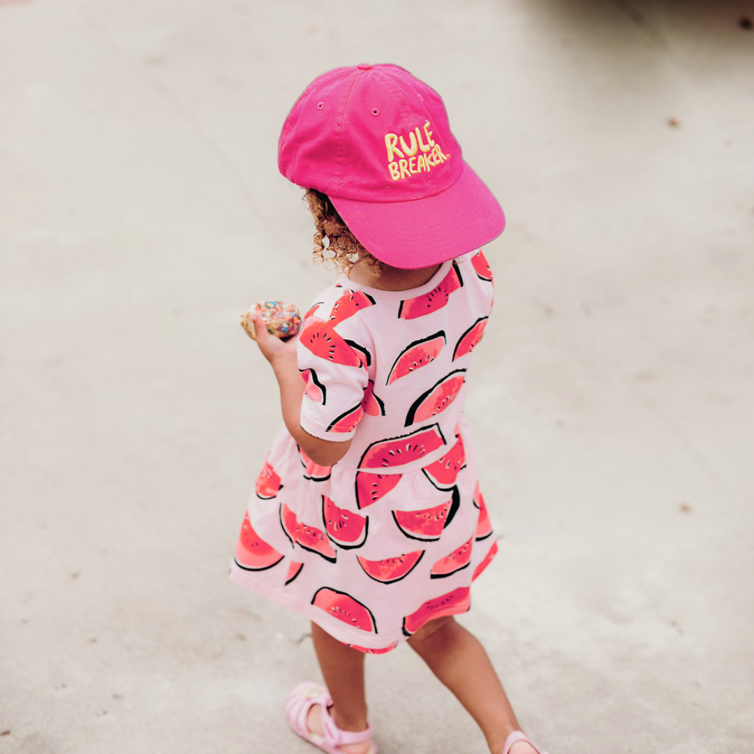 Little kid wearing a pink hat with yellow rule breaker logo