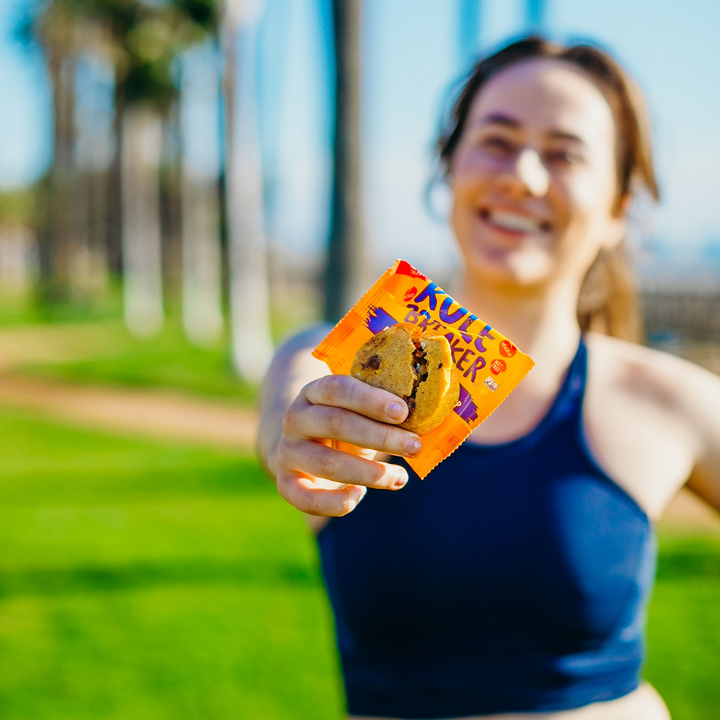 Woman working out and showing Rule Breaker Snacks P'Nutter Chocolate Chip blondie