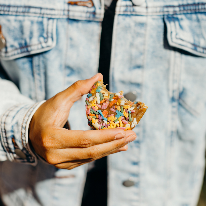 Rule Breaker Snacks Birthday Cake Singles woman holding in front of her